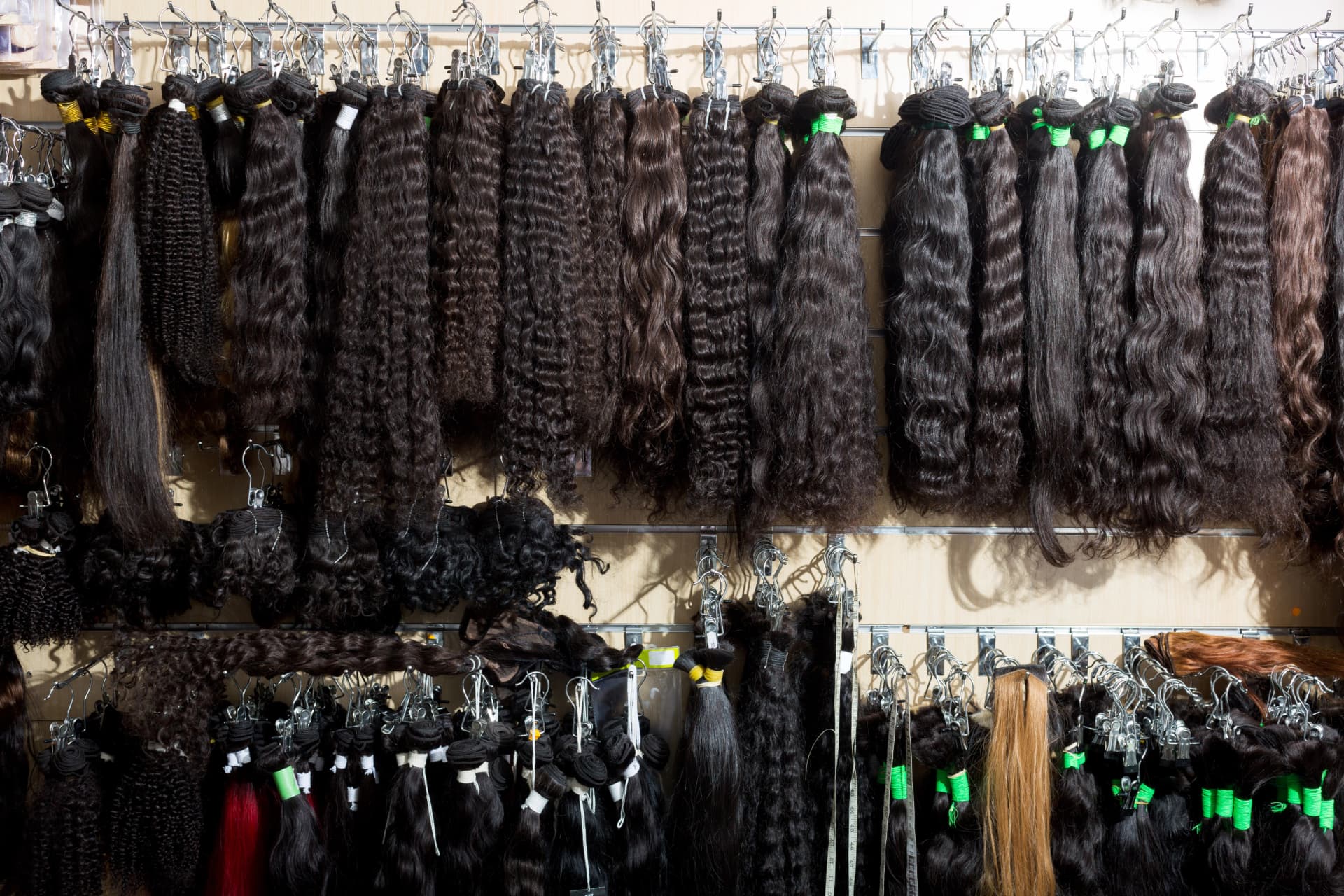 A wall of graded Indian hair bundles hanging by texture and length, ready for dispatch