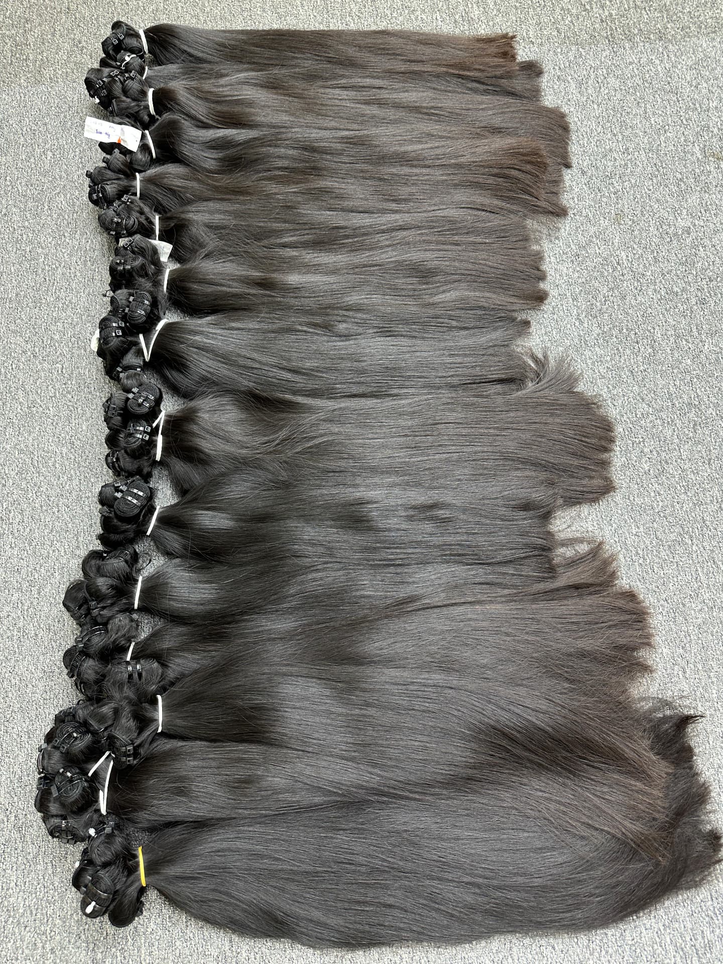 Row of natural straight temple-hair bundles tied and tagged for dispatch