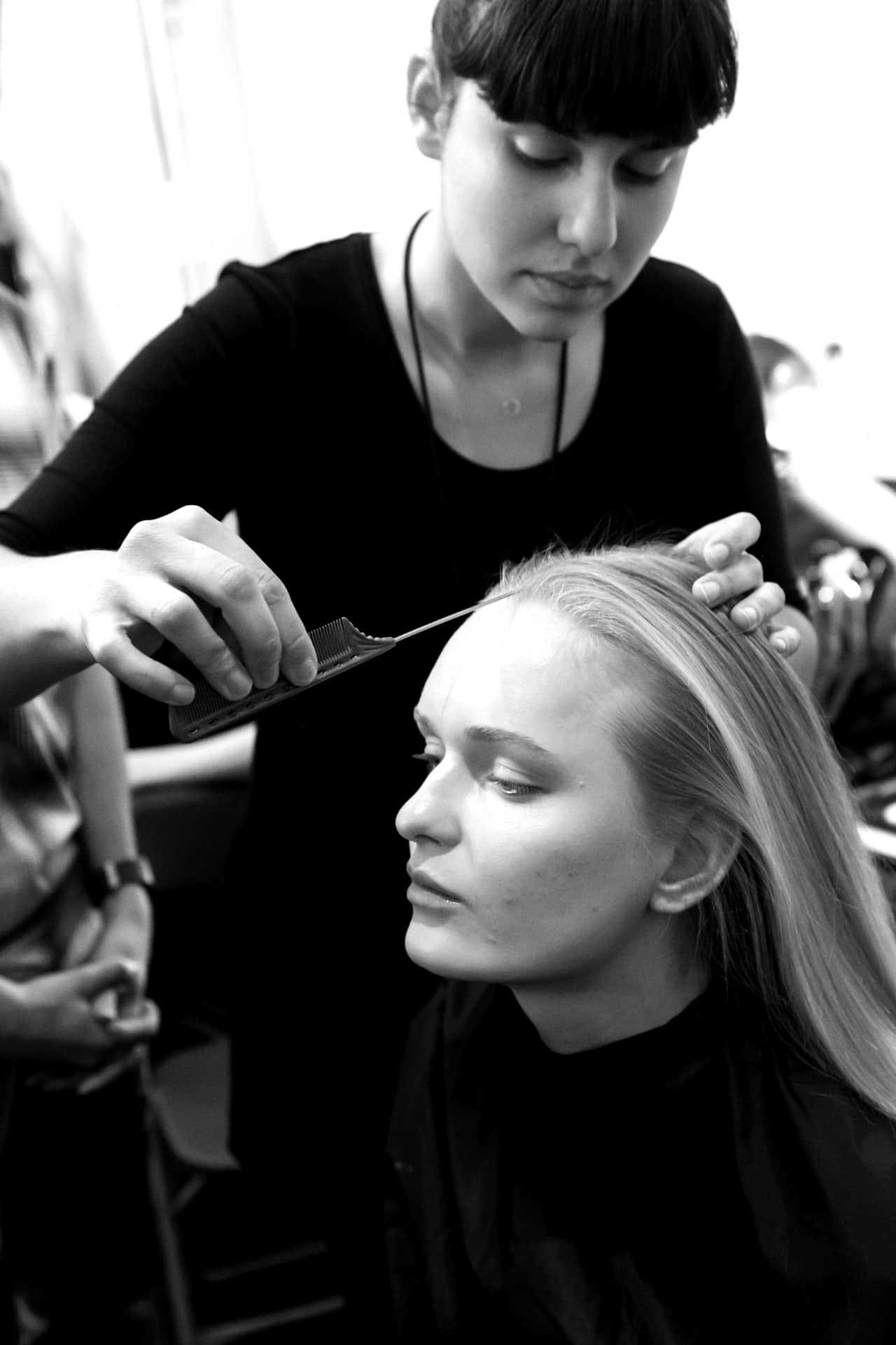 Stylist sectioning fine blonde hair with a tail comb