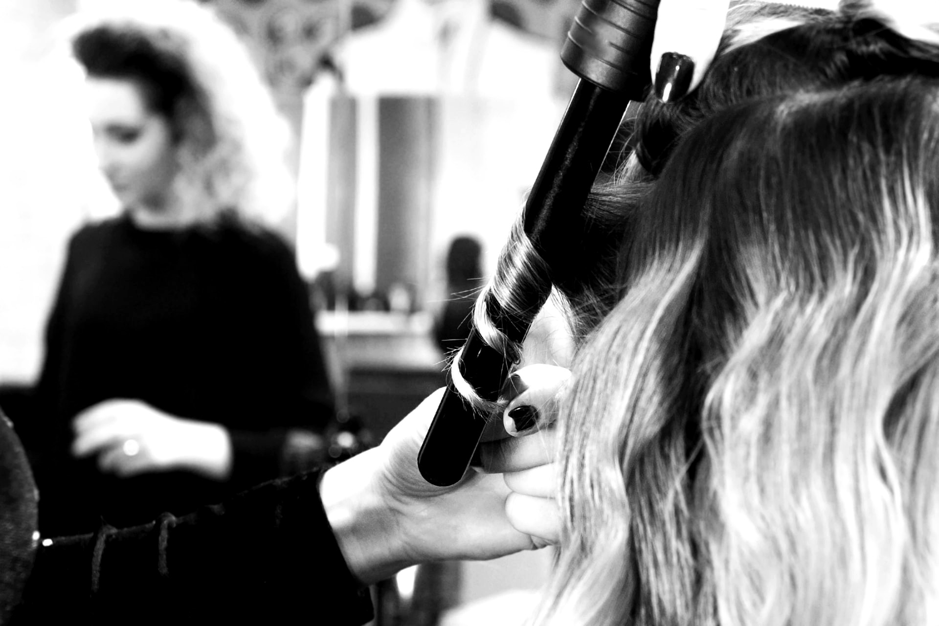 Close-up of a curling wand forming a polished curl on extension-length hair