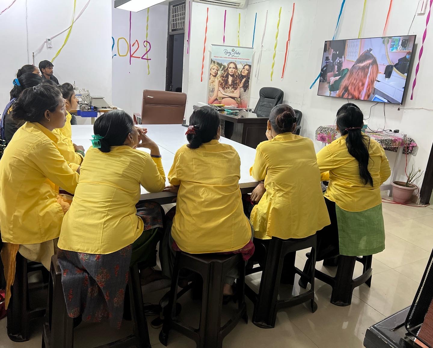 RemyPatra workers in yellow uniforms reviewing installation technique on the training screen
