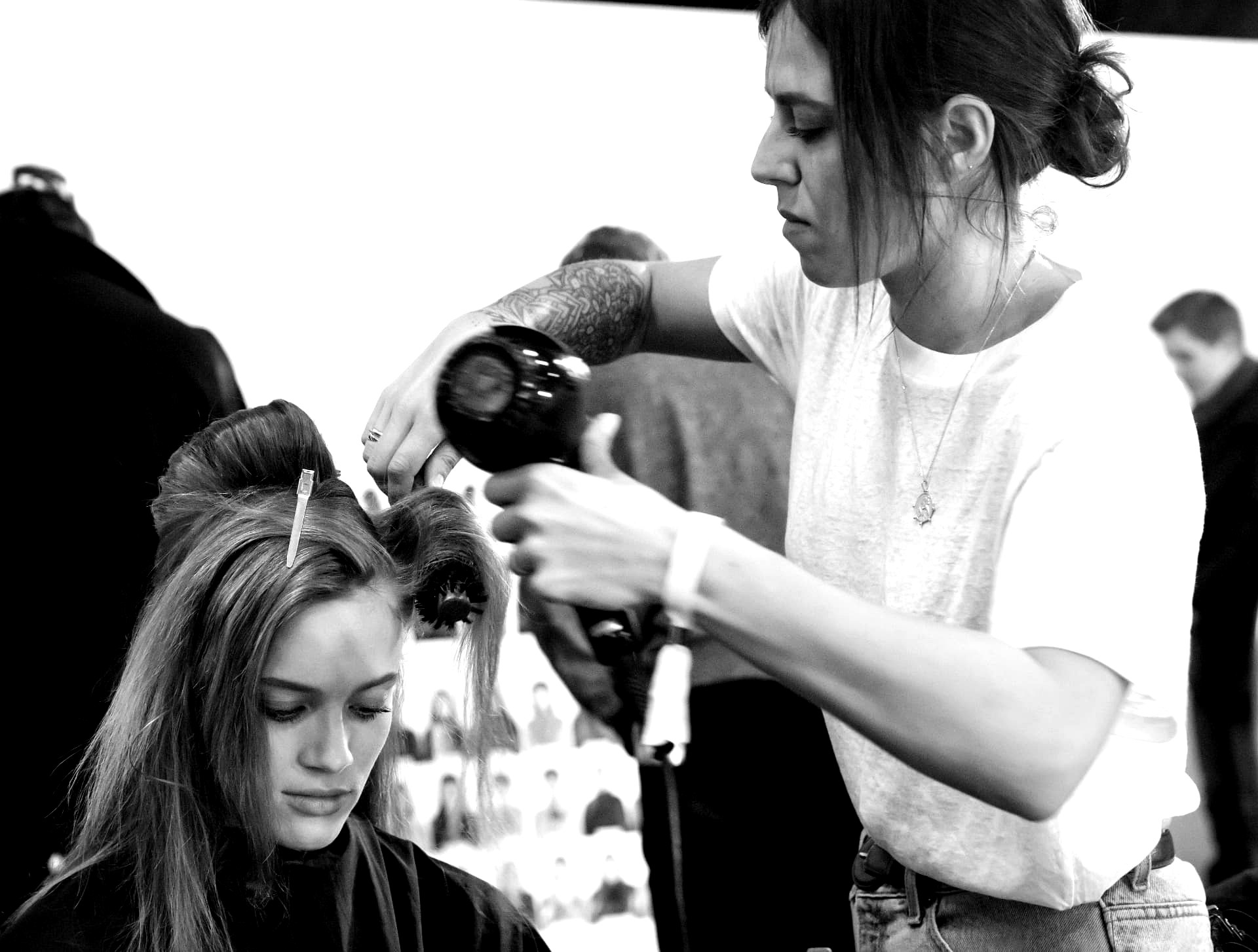 Stylist blow-drying and shaping sectioned hair backstage