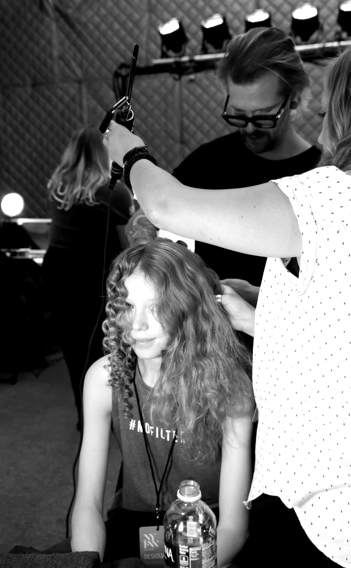 Stylist building volume and curl on long hair under show lighting