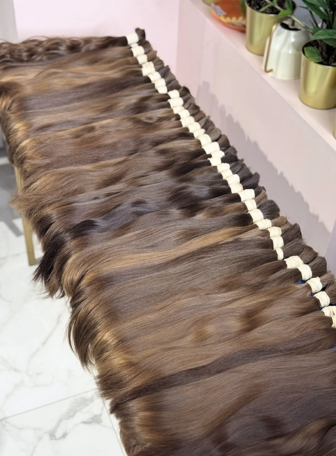 Single drawn brown virgin bundles laid out in a row after hackling, string-tied at the root