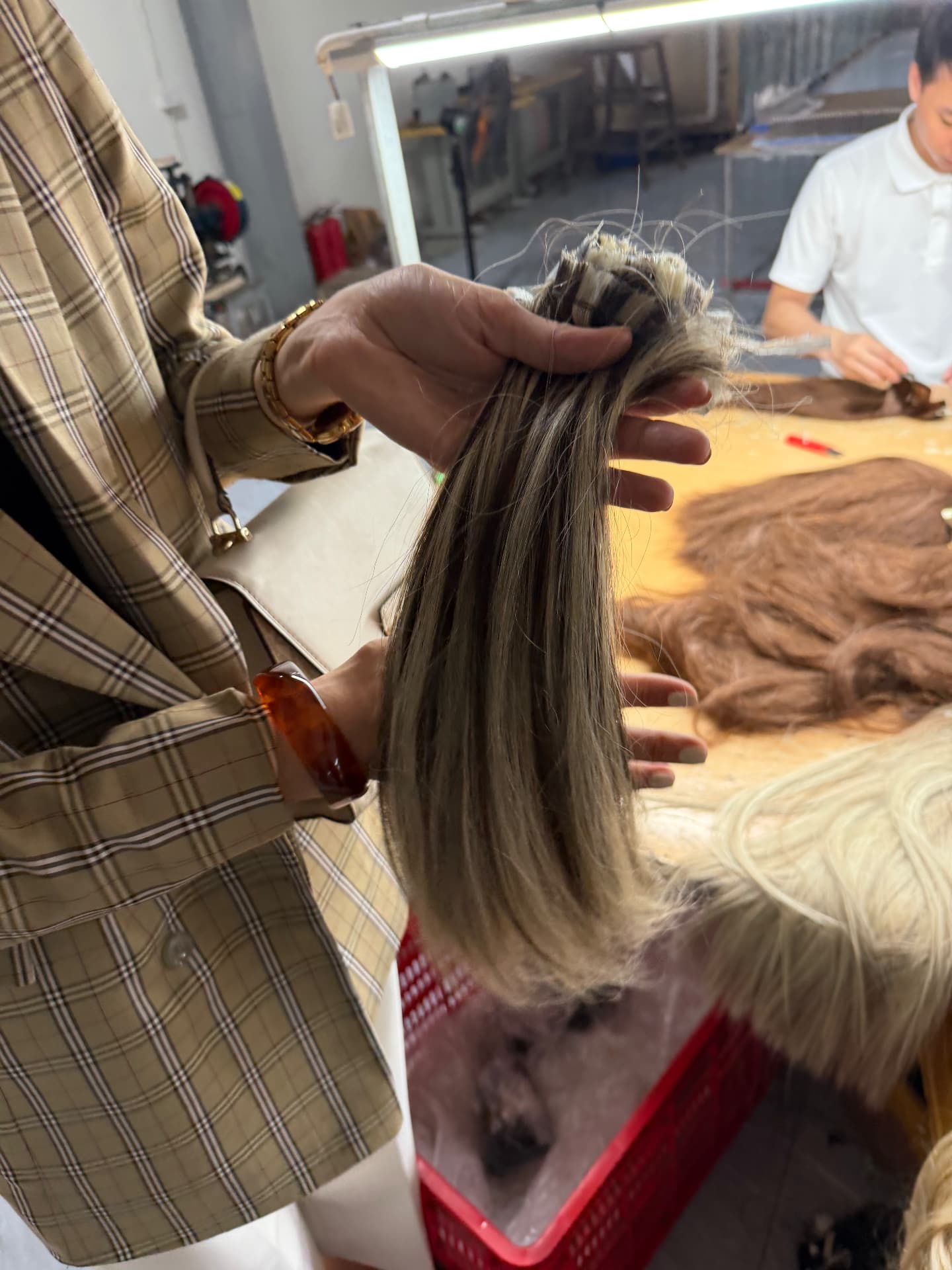 Finished highlighted extension hair checked by hand beside the production table in Manipur