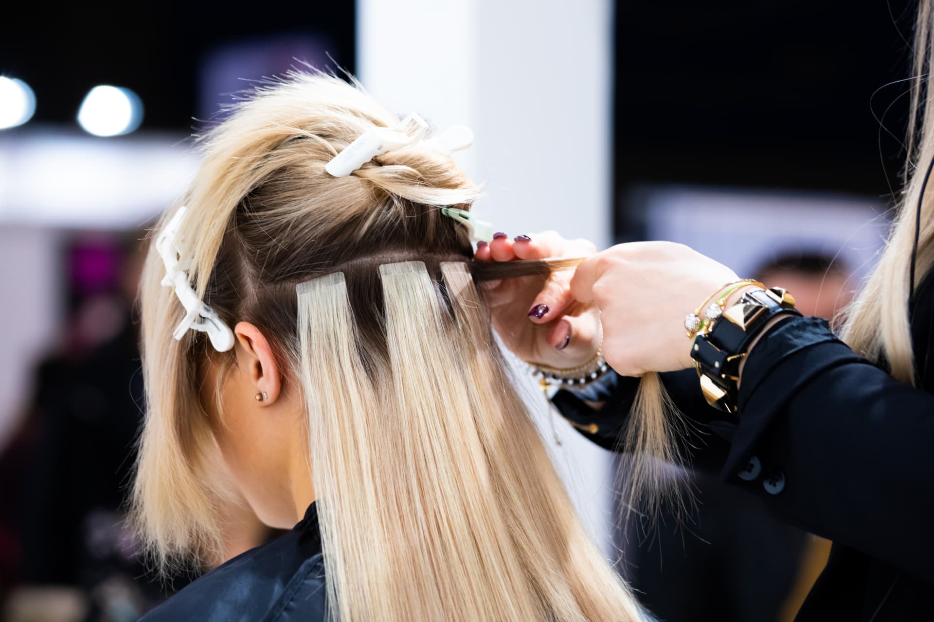 Stylist applying tape-in extensions in the salon