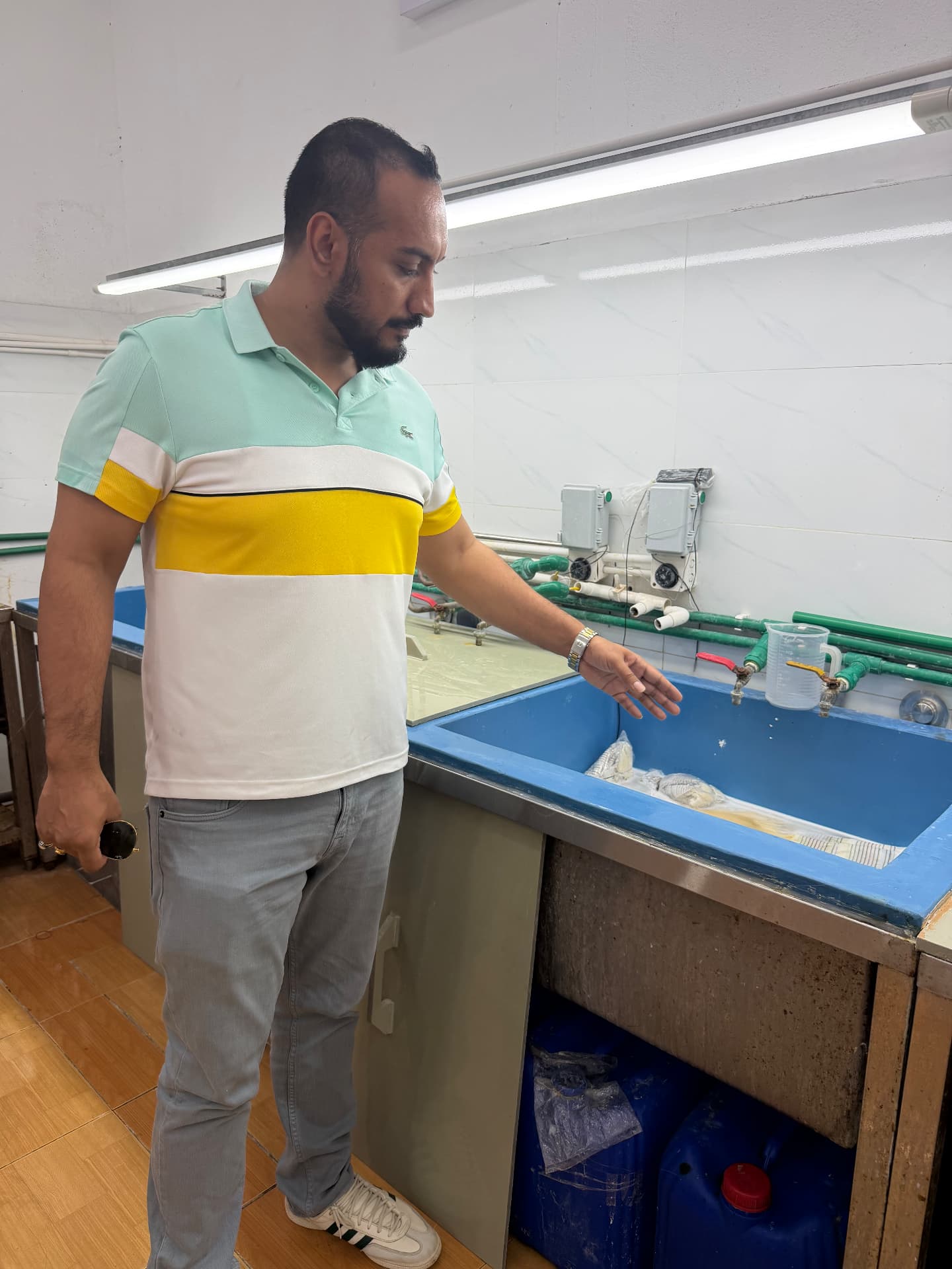 RemyPatra founder checking a lot in the washing bay, with measuring jug and timed water lines behind