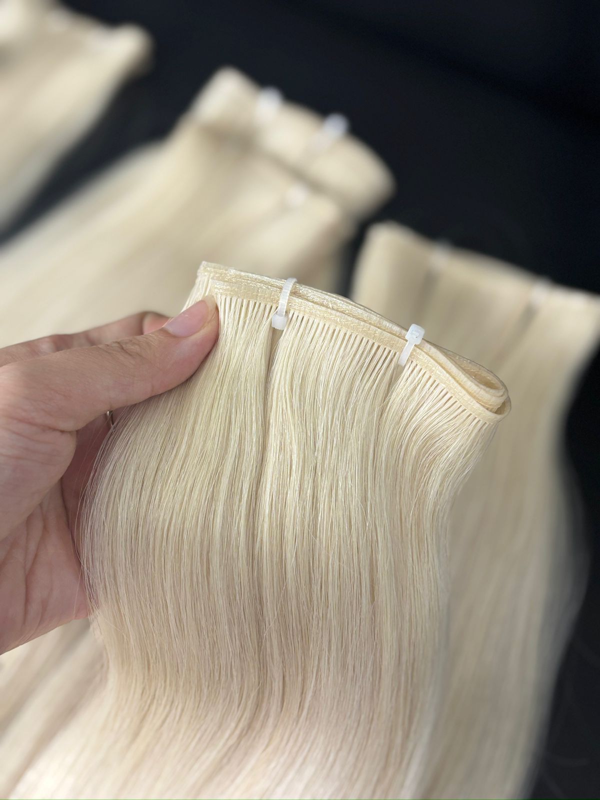 Platinum blonde Genius Weft held open to show its ultra-thin sealed seam