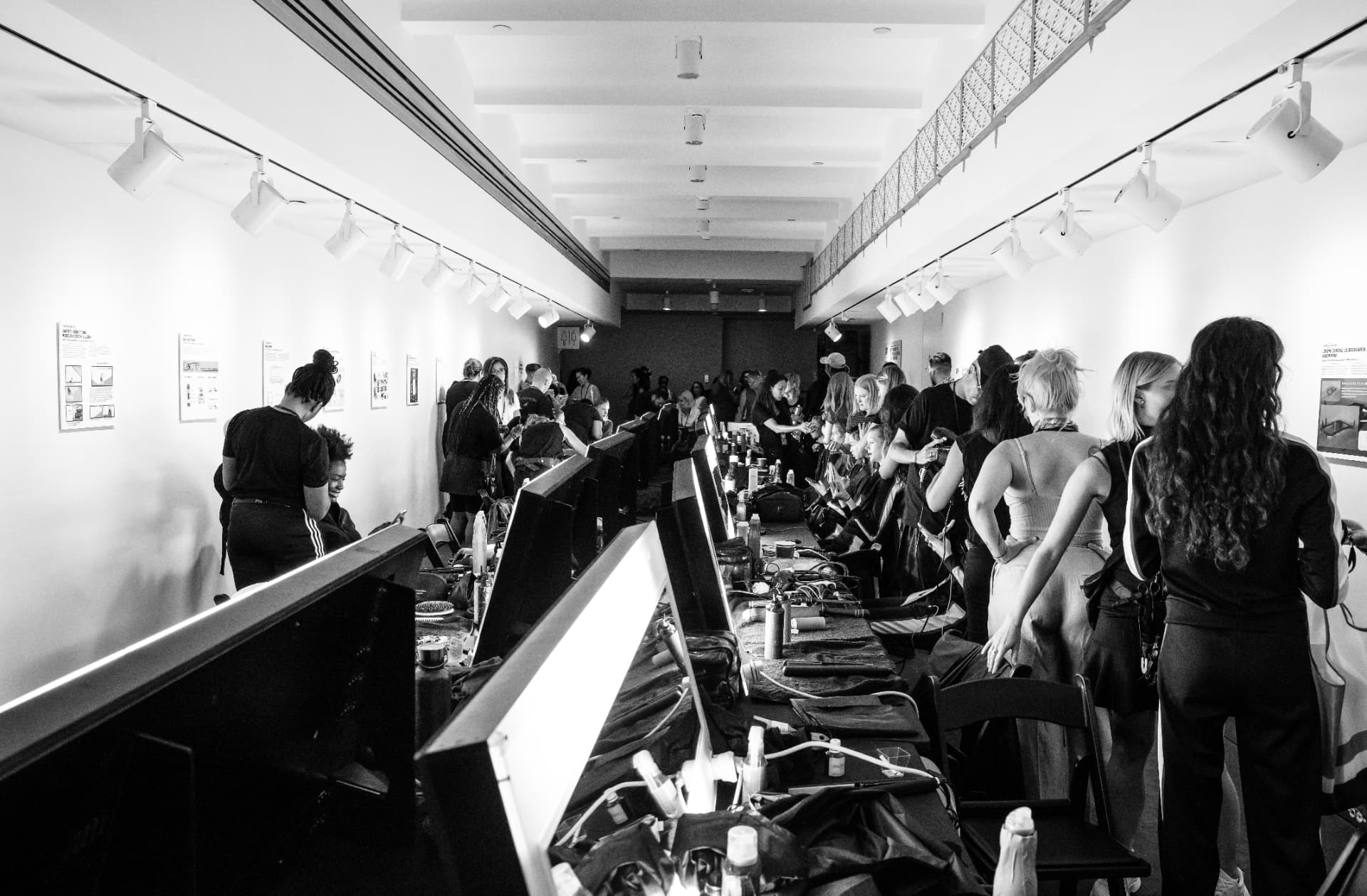 Long backstage corridor of lit mirror stations before a runway show